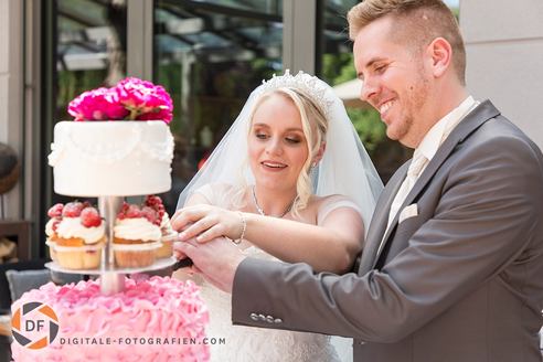 Das Brautpaar schneidet gemeinsam die Hochzeitstorte an – ein festlicher und symbolischer Moment, der die Freude und den Beginn ihres gemeinsamen Lebensweges feiert.